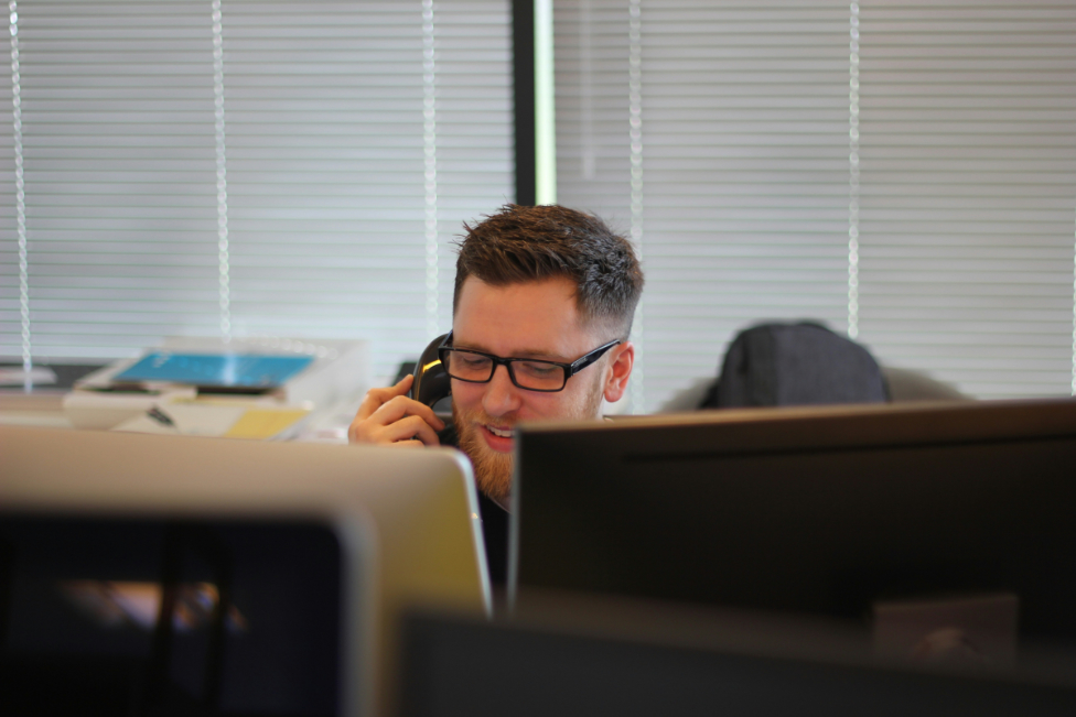 Mitarbeiter am Telefon hinter Monitoren – Kontaktaufnahme mit der GeBA Baustein GmbH