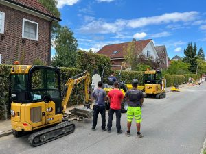 Mehrere Mitarbeiter und Baufahrzeuge der GeBA Baustein GmbH bei Straßenbauarbeiten